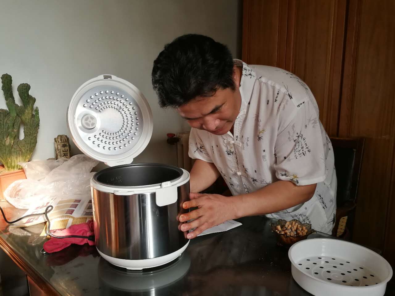 一位低视力残疾人正在学着自己使用语音盲文电饭煲